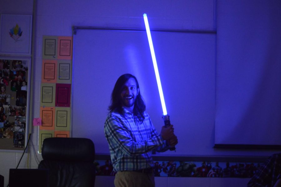Teacher Brandon Mudd displays his lightsaber in hand with a smile (Nov. 11)