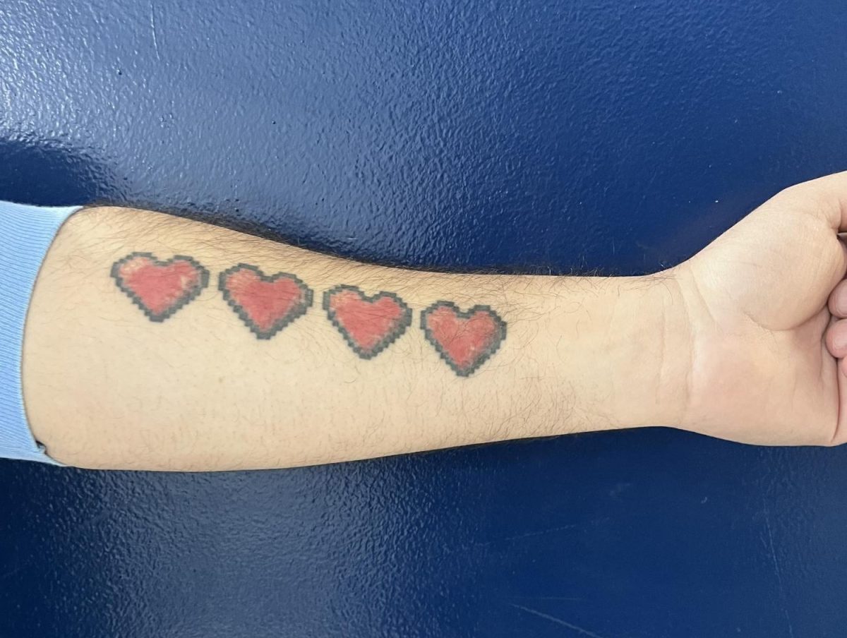 Art teacher Antonio Menendez reveals the life bar tattoo on his forearm. The hearts represent his wife and three kids.