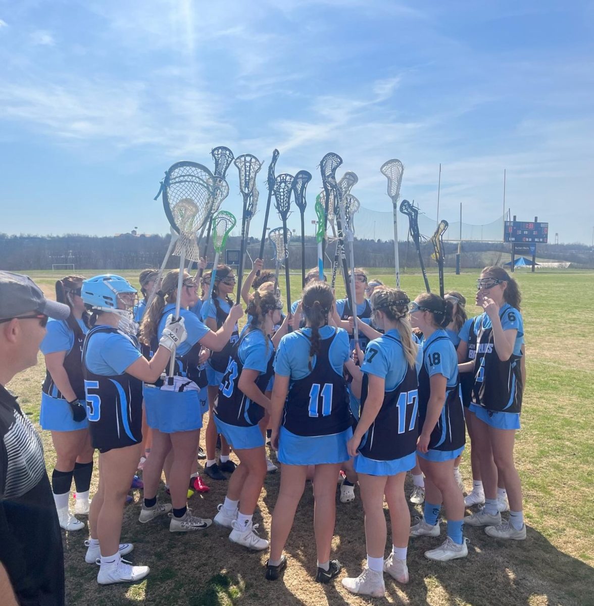 The+%E2%80%98Lady+Bruin%E2%80%99+Lacrosse+Team+readying+up+for+a+match+by+collaboratively+raising+their+lacrosse+sticks+in+a+team+huddle.+Photo+courtesy+of+senior+lacrosse+player+Alexis+Anderson.+