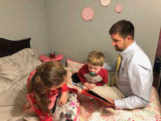 FACS teacher Jeanice Charlton's husband, Adam, reads at bedtime to their children, Porter (then 20 months) and Adalynn (then 3 years). Reading to children is one way that adults can help ensure that they grow up with strong literacy skills. Photo courtesy of Jeanice Charlton.