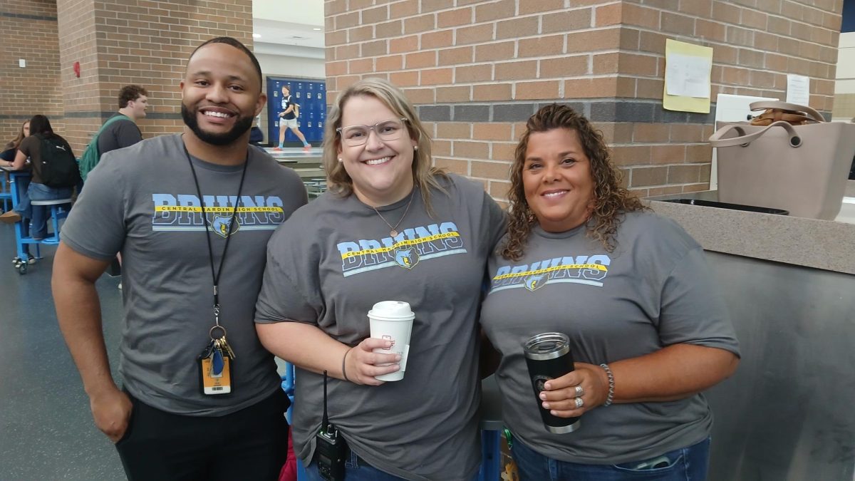 Boys' basketball coach Tavon Johnson, assistant principal Emily Wortham, and teacher Amy Pritt sport their '25-26 faculty shirt while on morning duty Aug. 8. Teachers were awarded their first spirit day of the year after sophomore Tate Loving sank a free throw in the first-day assembly on Aug. 7.