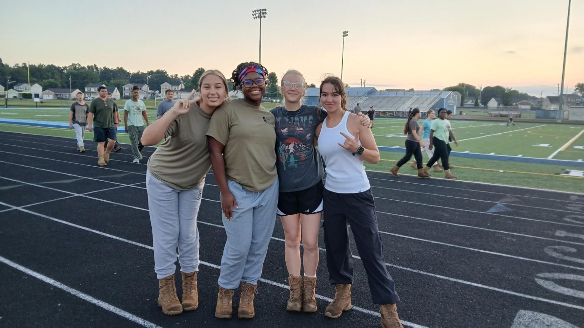 Sophomore Alexia Fair and seniors Mya Johnson, Alex Mcdonald, and Mia Washington smile during JROTC Raider Team practice on Aug. 21. 