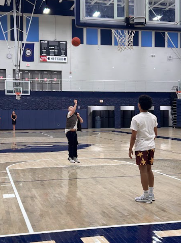 Upon being challenged by principal Kim Case to make a free throw as 1,800 peers watch, sophomore Tate Loving secures a spirit day for faculty. Senior Camdyn Hogan stands by to cheer him on.